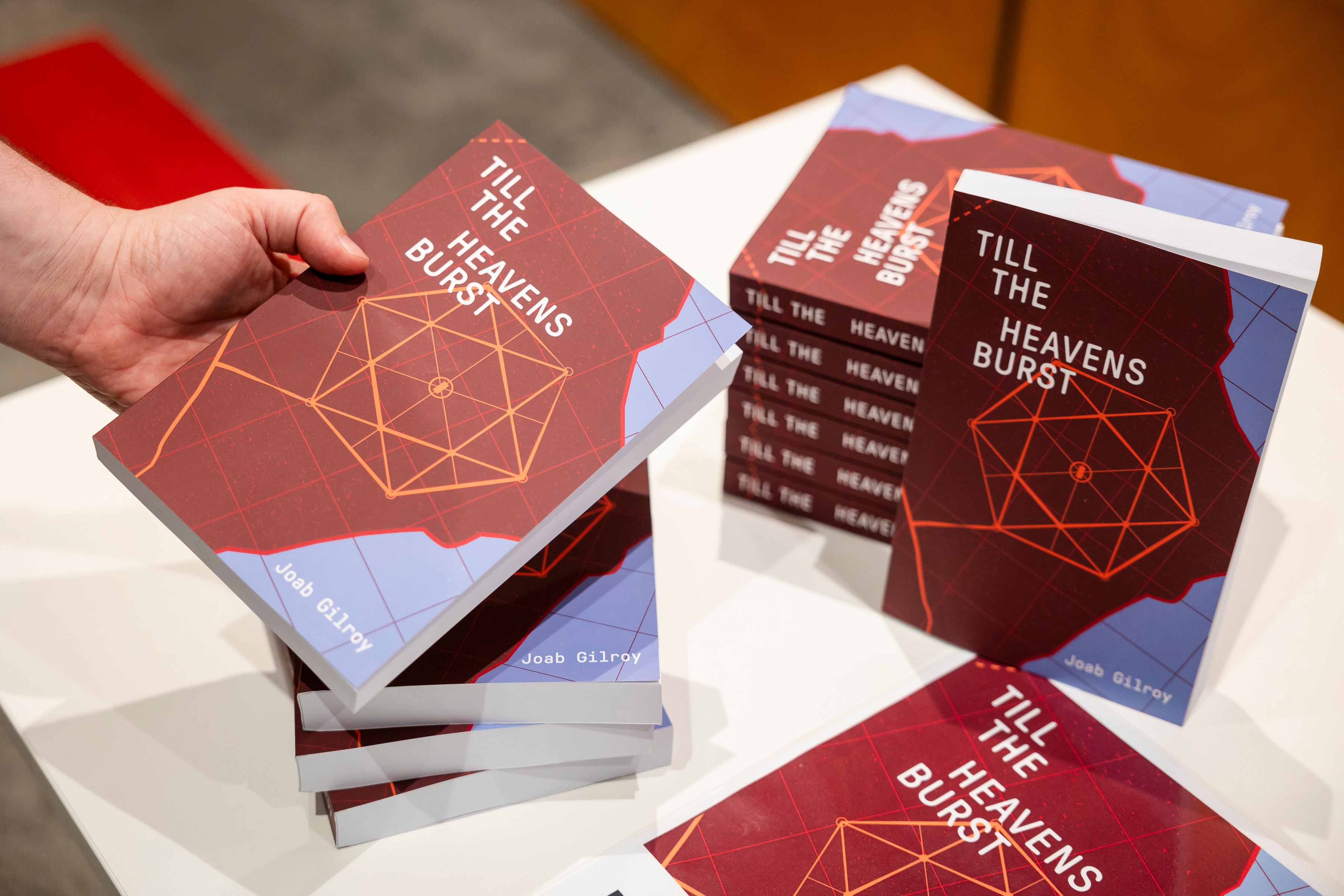 A stack of copies of Till The Heavens Burst on a desk